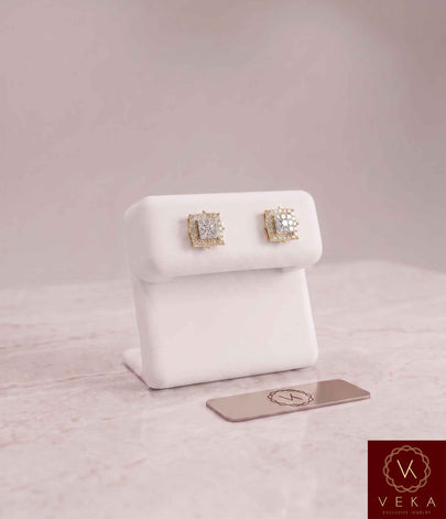 Pair of 0.35 CTW square halo natural diamond stud earrings set in 14K yellow gold, resting on a white Veka Jewelry display stand