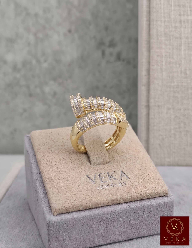 Professional studio shot of a VEKA Jewelry nail-shaped bypass ring in yellow gold, featuring 1.05 CTW of natural baguette and round-cut SI quality diamonds on a grey branded display.