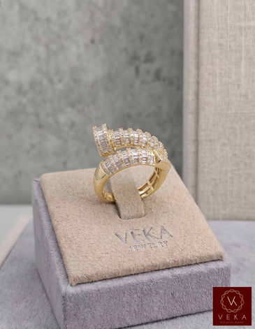 Professional studio shot of a VEKA Jewelry nail-shaped bypass ring in yellow gold, featuring 1.05 CTW of natural baguette and round-cut SI quality diamonds on a grey branded display.