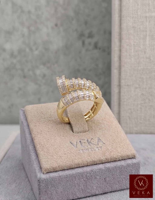 Professional studio shot of a VEKA Jewelry nail-shaped bypass ring in yellow gold, featuring 1.05 CTW of natural baguette and round-cut SI quality diamonds on a grey branded display.