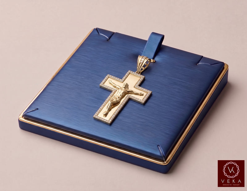 A 10K gold crucifix pendant with a detailed figure of Jesus, set against a textured blue presentation box with gold trim, on a neutral beige background with Veka Jewelry
