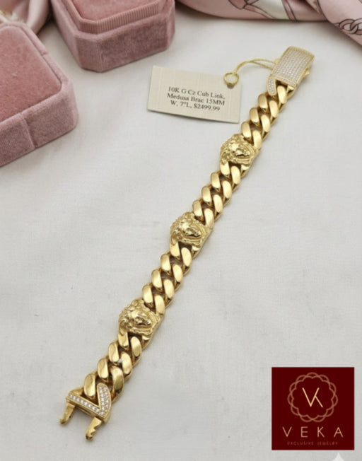A detailed top-down view of the 7-inch 10K gold Cuban link bracelet, showcasing the intricate Medusa heads, the polished 15.4mm links, and the specialized curved insert tongue with a sparkling cubic zirconia box clasp.