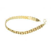 High-resolution detail of the 10K gold XOXO Stampato link pattern and polished finish on a 7.7mm wide women's bracelet.
