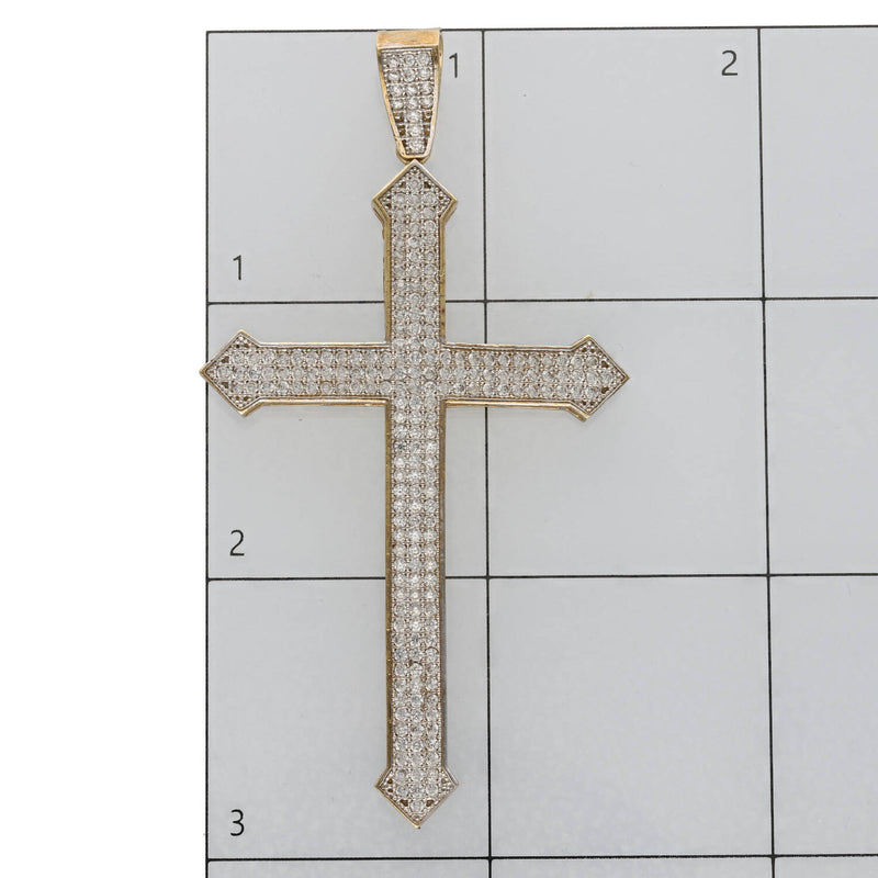 10K gold arrow edge cross pendant close-up showing CZ stones and pointed tips on a ruled grid to have a size reference