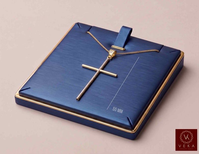 10K two-tone gold elongated cross pendant resting on a luxury navy blue leather display pad with gold trim.
