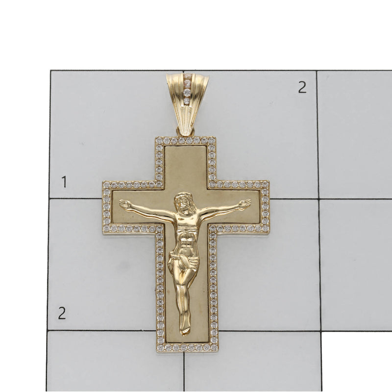 10K yellow gold Jesus crucifix pendant with cubic zirconia stones border on a white background with a ruled grid to serve a size reference.