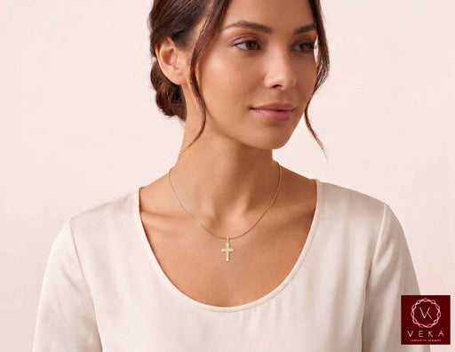 Delicate 10K yellow gold diamond cross pendant worn on neck chain by model - Veka Jewelry