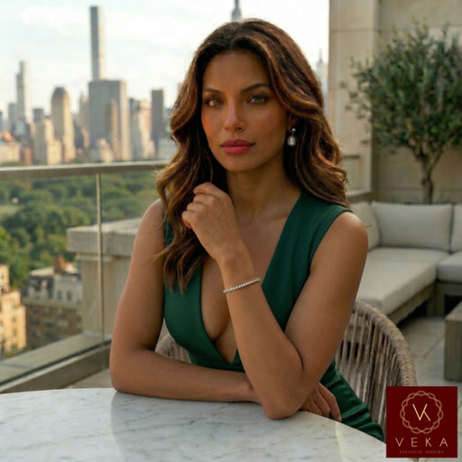 Elegant model wearing a 10k yellow gold tennis bracelet with 5.10ctw VVS moissanite stones on a luxury city balcony at sunset.