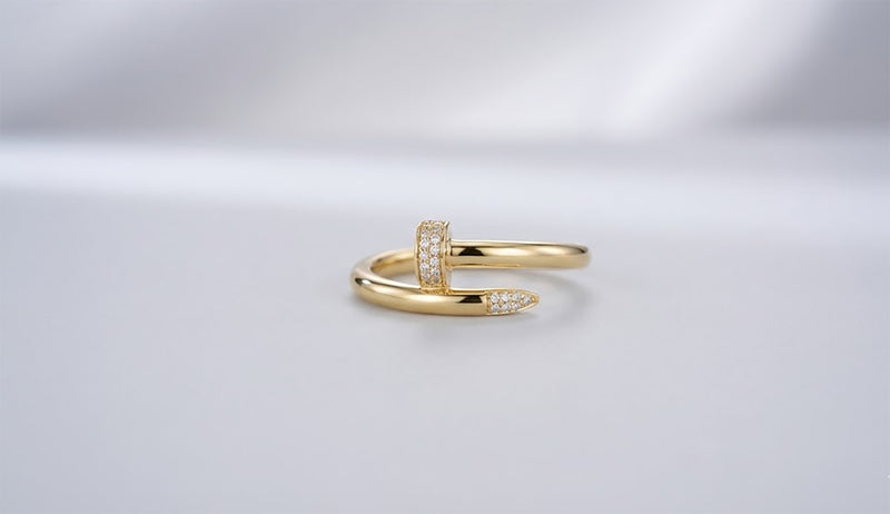 Studio shot of a 10K gold wrap ring designed like a bent nail, featuring pave cubic zirconia stones on the head and tip.