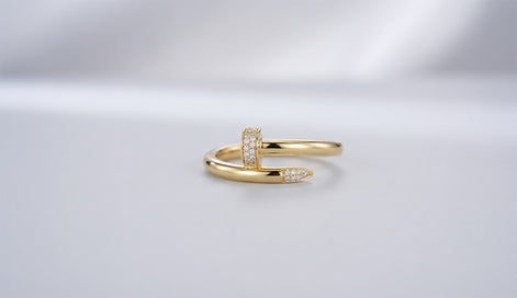 Studio shot of a 10K gold wrap ring designed like a bent nail, featuring pave cubic zirconia stones on the head and tip.