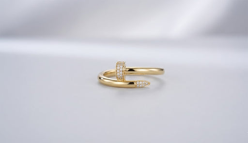 Studio shot of a 10K gold wrap ring designed like a bent nail, featuring pave cubic zirconia stones on the head and tip.