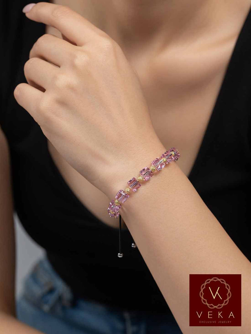 Close-up of 10K yellow gold pink Swarovski crystal adjustable bracelet on woman’s wrist showing macrame closure