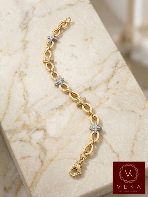 Close-up of a 10k two-tone gold bracelet with five CZ star charms on a white marble background, showing 7mm oval rolo links