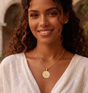 Lifestyle view of female model wearing the 10K two-tone gold Santa Barbara diamond-cut charm pendant with gold chain necklace by Veka Jewelry