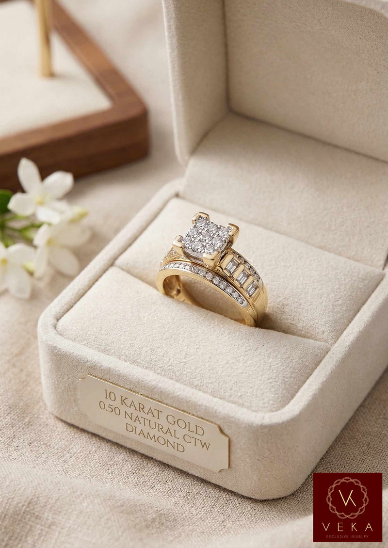 A high-angle view of the VEKA Cinderella style 10k yellow gold engagement ring. The ring, which features a cluster setting of round and baguette diamonds and a split-shank integrated band, is presented in a premium beige velvet ring box on a linen background. The front of the box has a plaque engraved with "10 KARAT GOLD | 0.50 NATURAL CTW | DIAMOND". White jasmine flowers are softly blurred in the background.