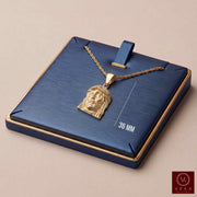 10K yellow gold Jesus face pendant with cubic zirconia crown presented on a blue and gold luxury jewelry display pad with chain by Veka Jewelry.