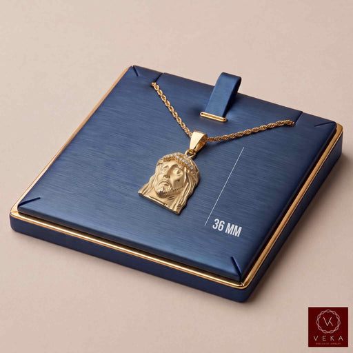 10K yellow gold Jesus face pendant with cubic zirconia crown presented on a blue and gold luxury jewelry display pad with chain by Veka Jewelry.