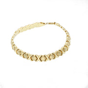 Detailed product view of a 7-inch women's XOXO bracelet in 10K yellow gold. The image highlights the intricate "Hugs & Kisses" Stampato link pattern and the brilliant reflective quality of the polished gold.