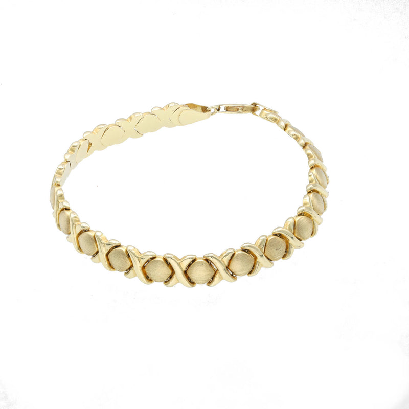 Detailed product view of a 7-inch women's XOXO bracelet in 10K yellow gold. The image highlights the intricate "Hugs & Kisses" Stampato link pattern and the brilliant reflective quality of the polished gold.