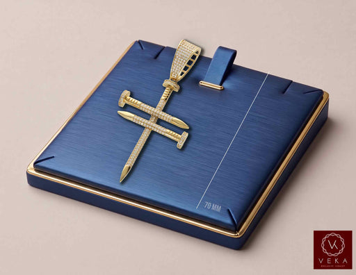 A 14K gold cross with nails pendant encrusted with clear stones, displayed on a blue textured jewelry box with gold trim. The box features a measurement marker indicating 70 mm.