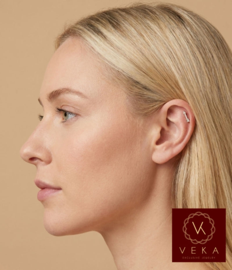 Close-up of a model wearing a 14k gold arrow flat back stud with cubic zirconia in a helix piercing. Internally threaded cartilage jewelry by VEKA Jewelry.