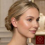 Model wearing a dainty 14K yellow gold ear cuff with a heart and crown design on the upper helix of the ear. Non-pierced gold jewelry by VEKA Jewelry