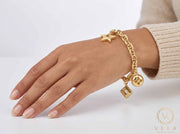 Woman wearing an authentic 14K yellow gold 6mm mariner link charm bracelet on wrist - fine jewelry lifestyle by Veka Jewelry.
