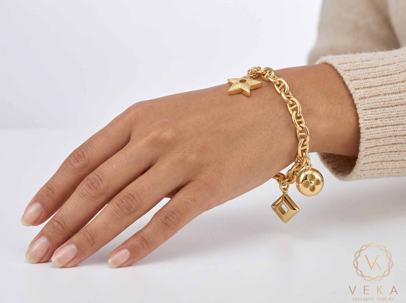 Woman wearing an authentic 14K yellow gold 6mm mariner link charm bracelet on wrist - fine jewelry lifestyle by Veka Jewelry.