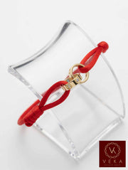14K gold two band passion red macrame bracelet with screw head design displayed on clear acrylic jewelry stand against white background