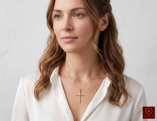 Female model wearing 14K yellow gold slim minimalist cross pendant on a delicate chain with white shirt