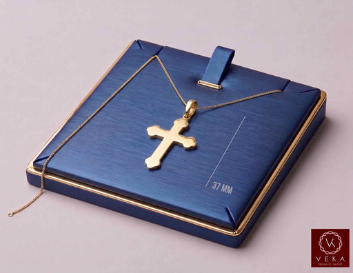 14K solid yellow gold budded cross pendant displayed on an elegant blue and gold jewelry tray with gold chain by Veka Jewelry