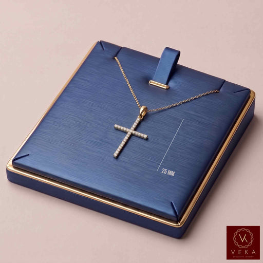 14K solid yellow gold slim cross pendant with 0.20 CTW natural diamonds on a luxury navy display stand, 25mm length - Veka Jewelry