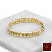 Professional studio shot of a 14k yellow gold 8.5mm Italian tight Cuban link bracelet showcased on a white marble pedestal, luxury fine jewelry by Veka