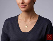 Woman wearing the 14K yellow gold beveled cross pendant on a gold chain necklace by Veka Jewelry.