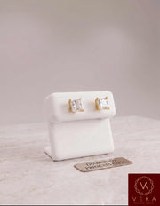 Pair of 2.11 CTW princess cut lab grown diamond stud earrings in 14k yellow gold on a white luxury display stand at VEKA Jewelry.