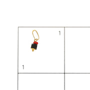 14k Gold azabache on a grid of 1 by 1 inch to see the scale of its size.