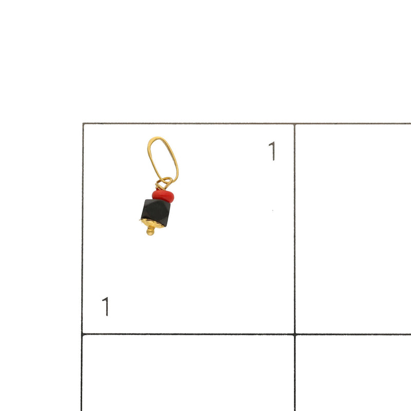 14k Gold azabache on a grid of 1 by 1 inch to see the scale of its size.