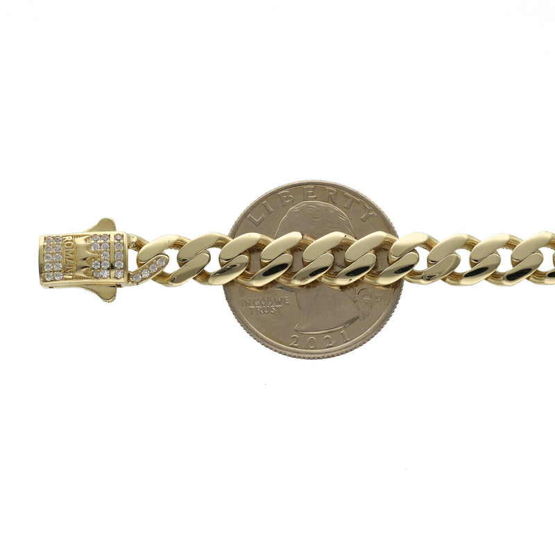 A 14 karat gold anklet with clear zirconia stones with the word ROMA, featuring a Cuban-link design shown on a white background on top of a 25 cent coin to have an idea of the regular size.