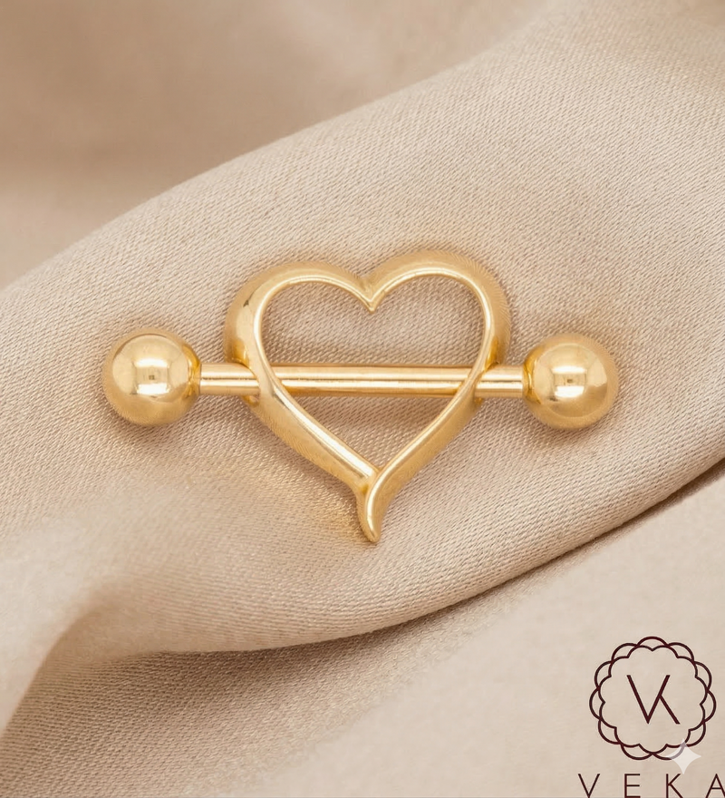 Gold heart-shaped barbell Nipple Piercing on a beige fabric silk background with Veka branding.