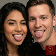 Two people sticking out their tongues with a 14k Gold Tongue Barbell Piercing with the logo a very well known jewelry