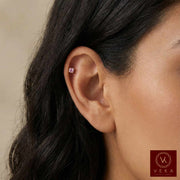 Close-up of an ear wearing a small 14k Gold earring flat back labret  with a blurred background, featuring the Veka brand.