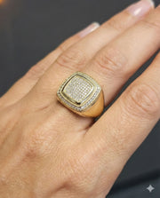 A male model wearing a 14k Gold ring with cubic zirconia accents on a grey wall on the back.