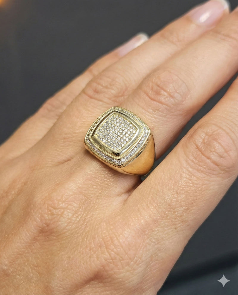 A male model wearing a 14k Gold ring with cubic zirconia accents on a grey wall on the back.