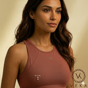 Close-up of a Latina model wearing a 14K gold dangle nipple piercing over a mauve athletic sports top - Veka Jewelry Lifestyle