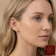 Close-up profile of a blonde woman wearing a 14k gold and pavé stone snake flat back stud in her upper helix cartilage piercing. Luxurious ear scape jewelry by VEKA Jewelry.