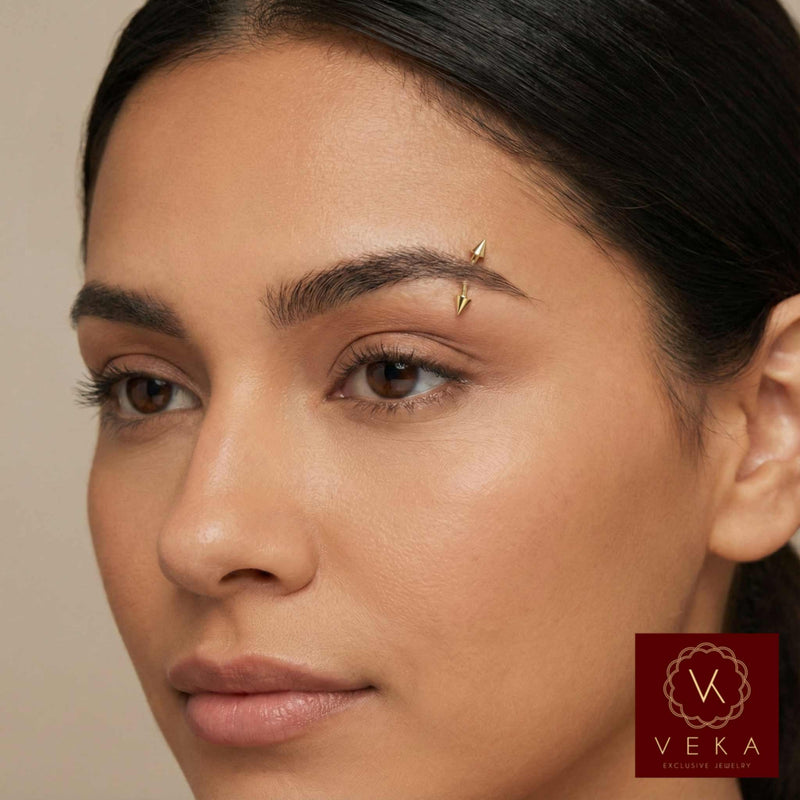 Close-up of a woman's face with a gold eyebrow pin, Veka logo in the corner.
