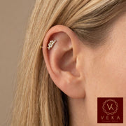 Close-up profile of a blonde woman wearing a 14k yellow gold and cubic zirconia leaf branch flat back stud in an upper helix cartilage piercing. Nature-inspired ear jewelry by VEKA Jewelry.