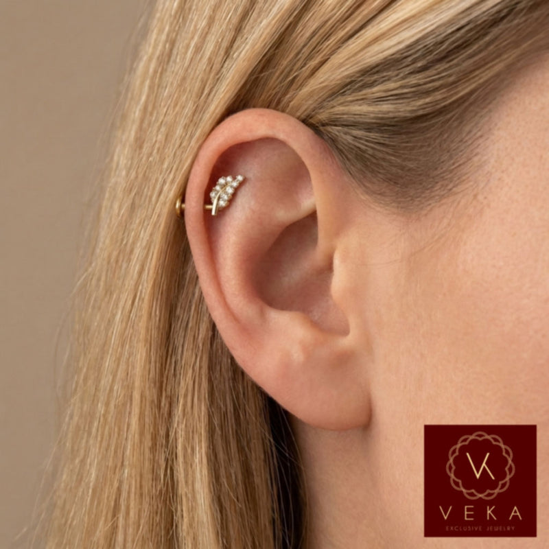 Close-up profile of a blonde woman wearing a 14k yellow gold and cubic zirconia leaf branch flat back stud in an upper helix cartilage piercing. Nature-inspired ear jewelry by VEKA Jewelry.