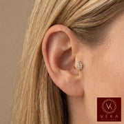 Close-up profile of a blonde woman wearing a 14k yellow gold and cubic zirconia leaf branch flat back stud in an upper helix cartilage piercing. Nature-inspired ear jewelry by VEKA Jewelry.