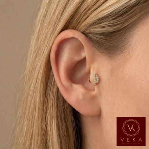Close-up profile of a blonde woman wearing a 14k yellow gold and cubic zirconia leaf branch flat back stud in an upper helix cartilage piercing. Nature-inspired ear jewelry by VEKA Jewelry.